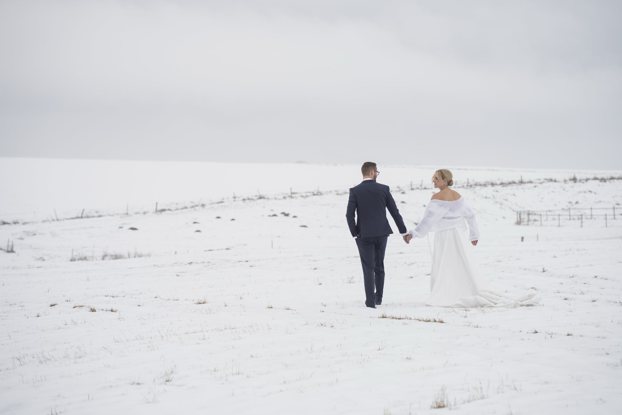 Lisa und Yannick gehen Hand in Hand durch die verschneite Landschaft bei ihrer Winterhochzeit im Sippelshof Fulda